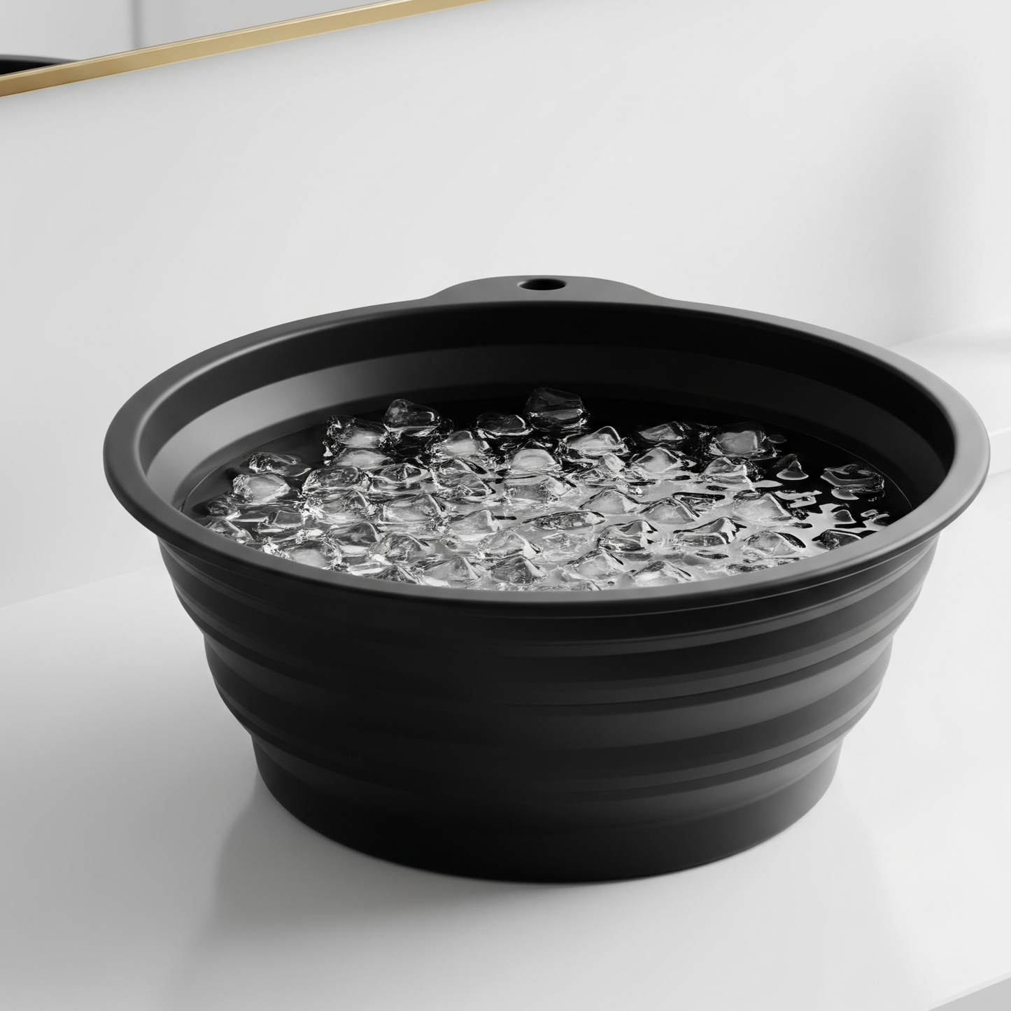 Black collapsible basin with ice cubes on a white surface